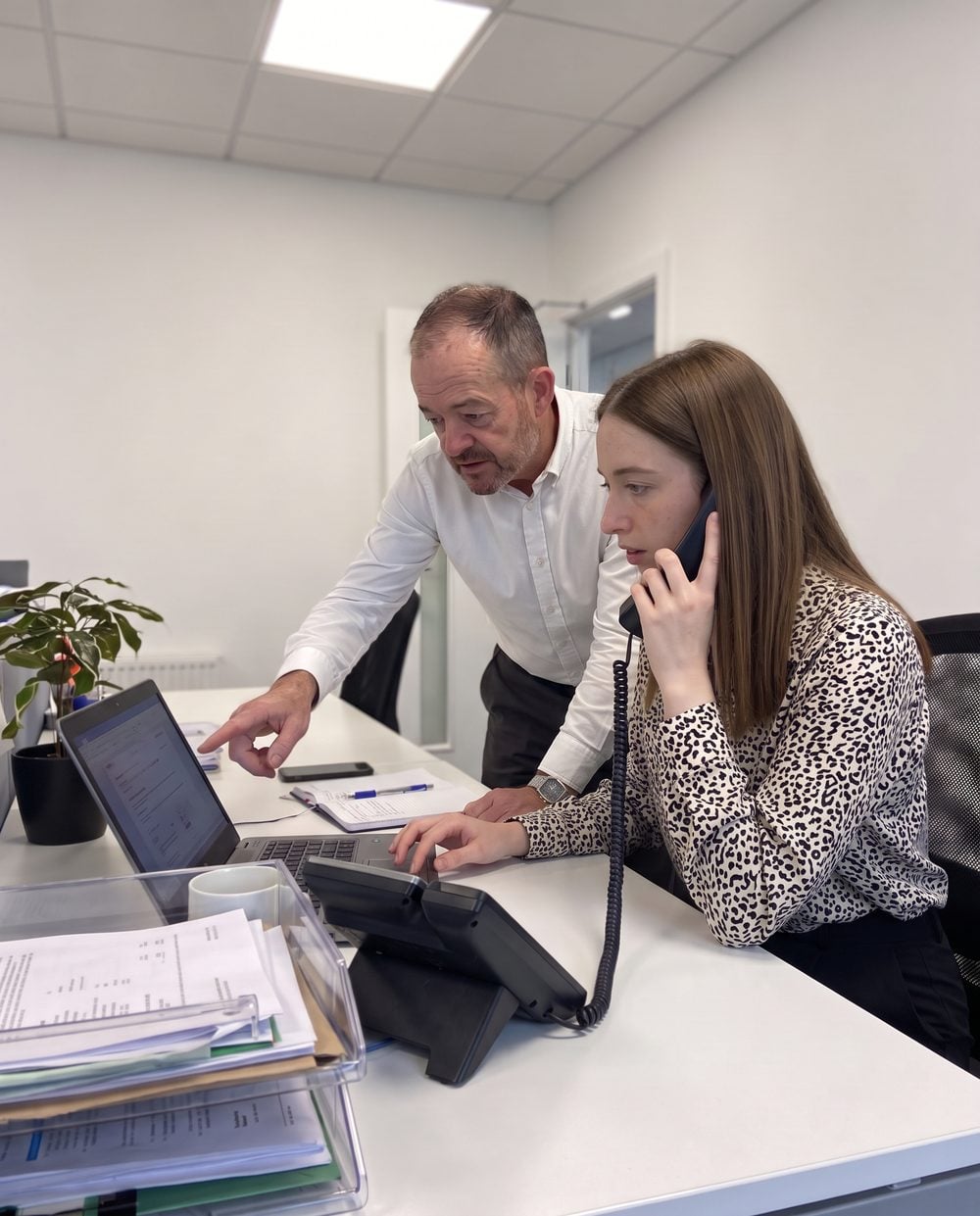 Two members of the Read & Associates team at a desk, one on the phone to a client