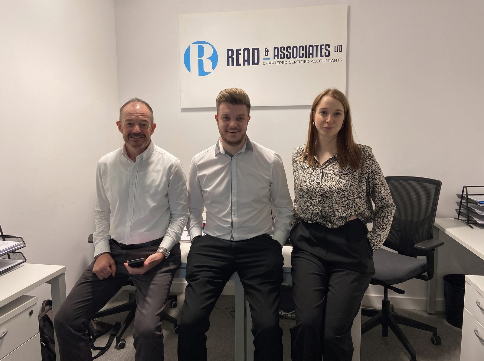 Blane Read and the Read & Associates team in their Milton Keynes office, under the company sign